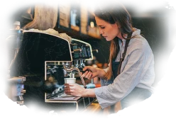 Female barista preparing coffee using espresso machine in a busy coffee shop